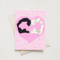 Greeting card of two cats in a pink heart with confetti all around.